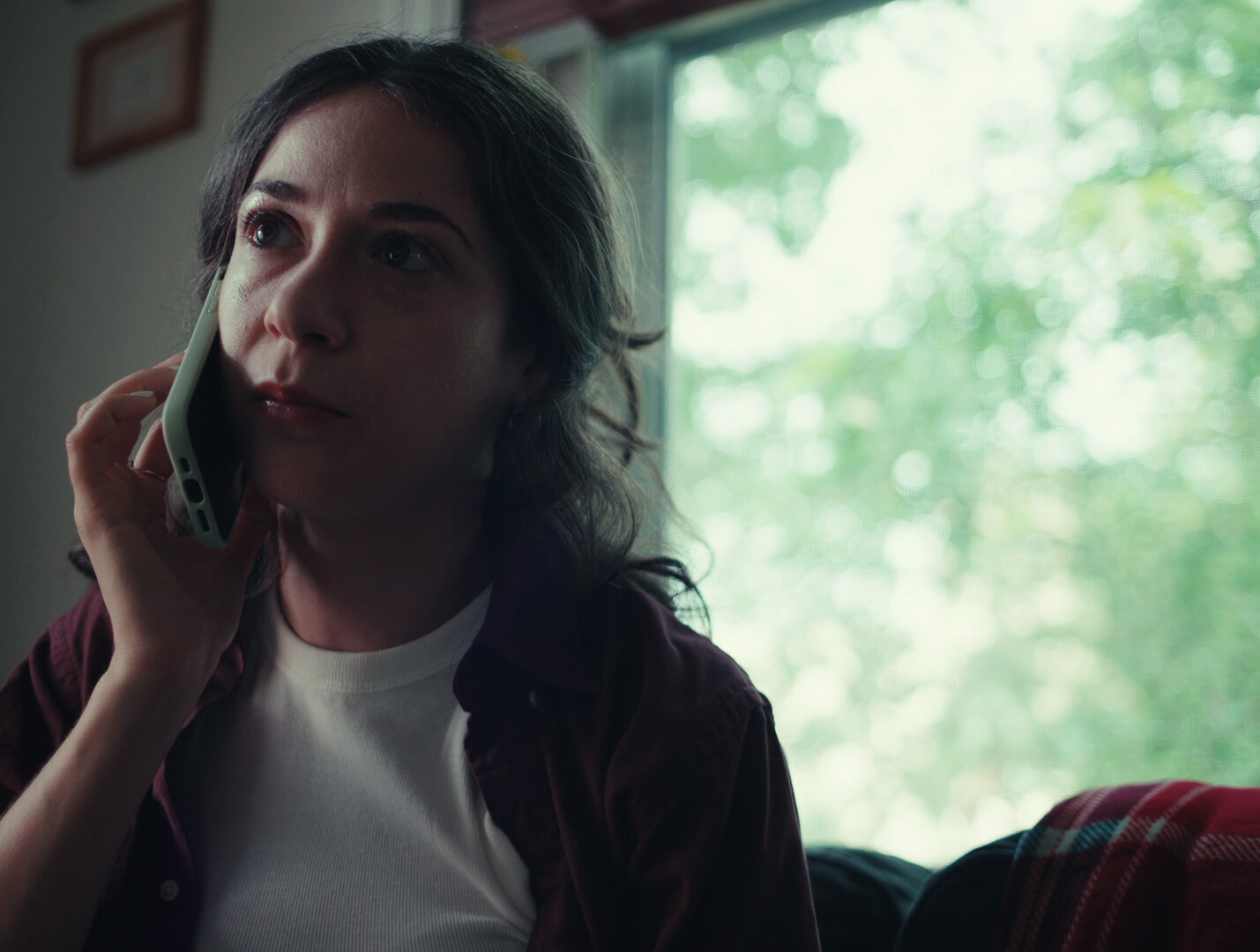 Still from The Flies: a woman on the phone by a window